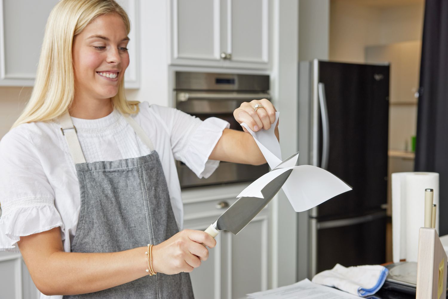 Person slicing a piece of paper with Material The 8-Inch Knife