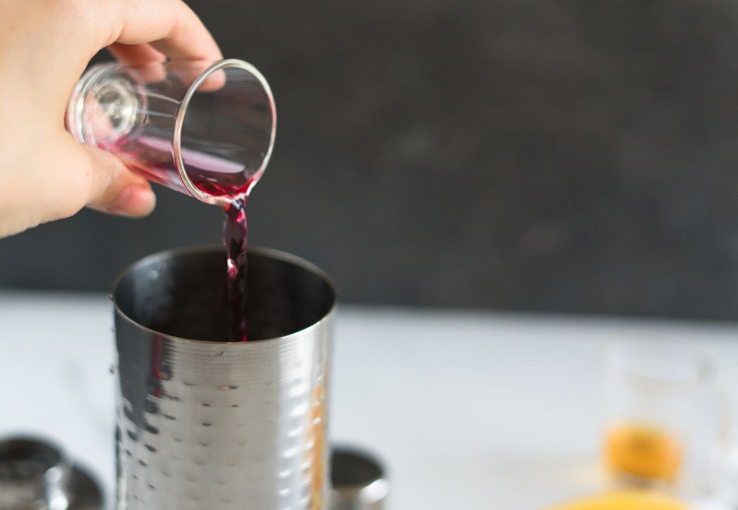 Rum runner ingredients being poured into cocktail shaker