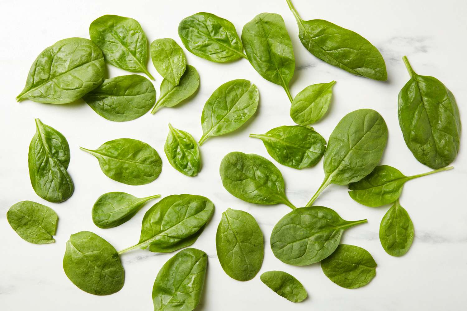Leaves of baby spinach scattered on a marble surface