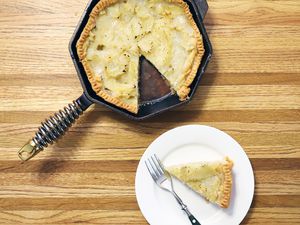 Finex Cast Iron Skillet displayed on butcher block counter with nearby white plate, piece of pie, and fork