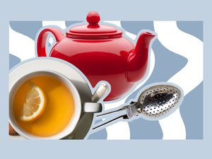 A cup of tea, teapot, and tea infuser spoon on a blue background