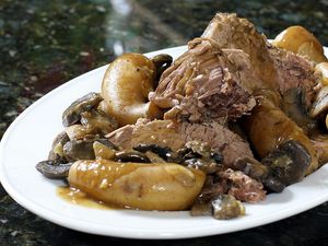 Pot roast with mushrooms and potatoes on a white plate