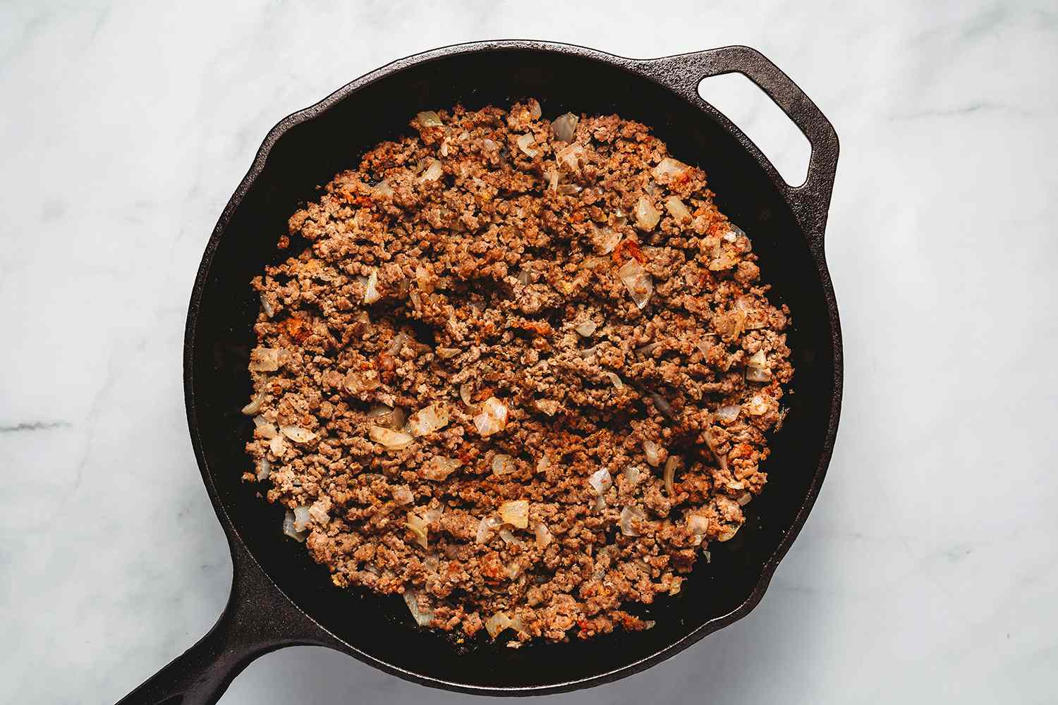 Tomato paste, garlic powder, onion powder, salt, and pepper with the beef mixture in a cast iron skillet