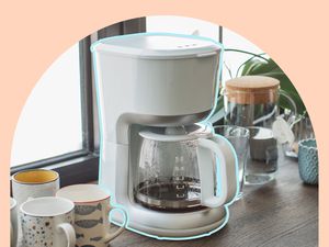 A drip coffee maker on a countertop surrounded by coffee mugs