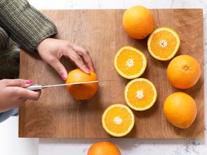 A woman cutting oranges on a cutting board