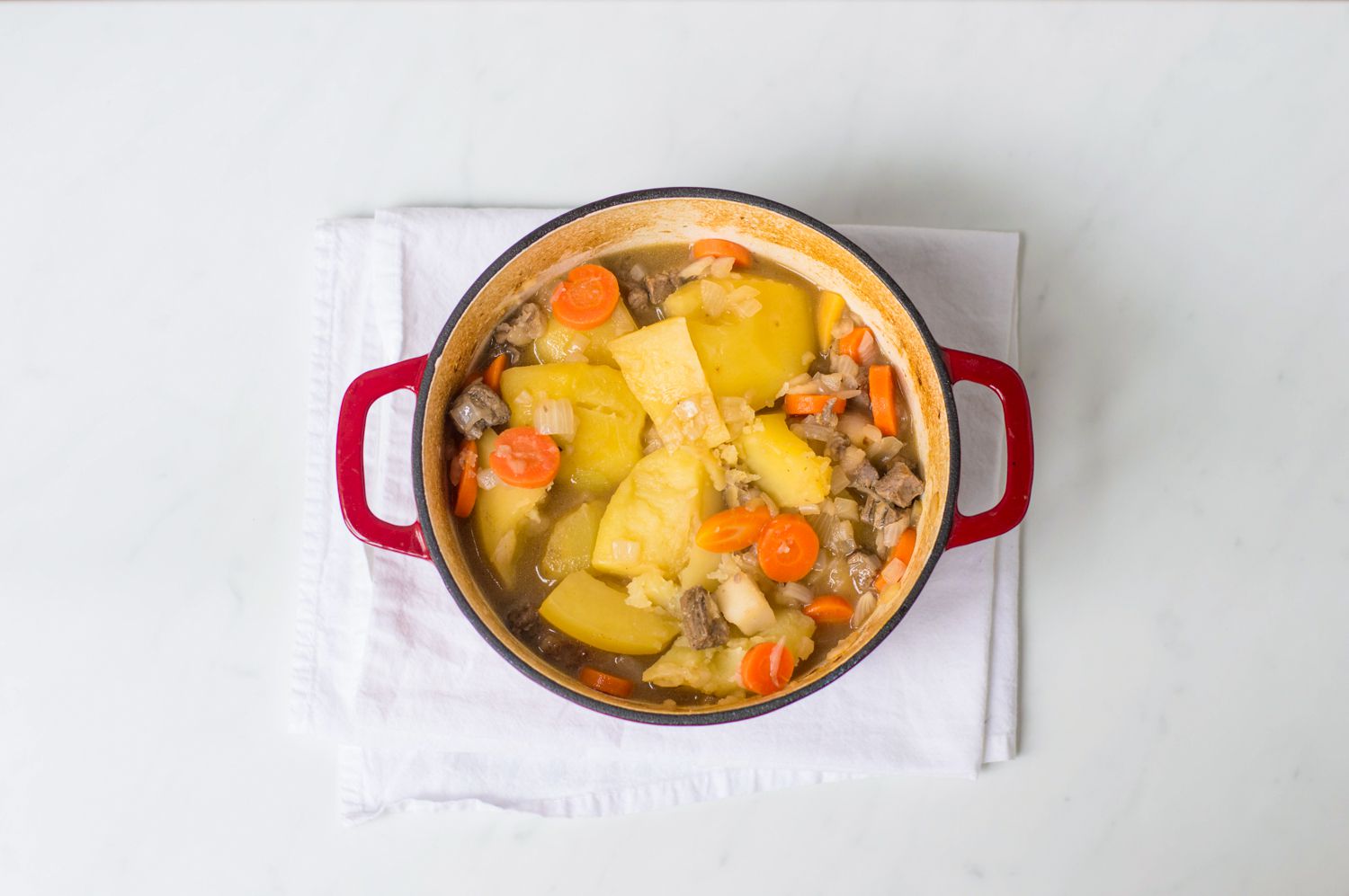 Vegetables added to Scottish stovies in a Dutch oven