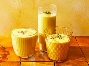 Three glasses of Mango Lassi garnished with saffron and nuts