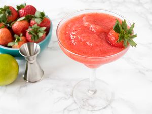  Frozen strawberry margarita in a glass with a bowl of strawberries nearby