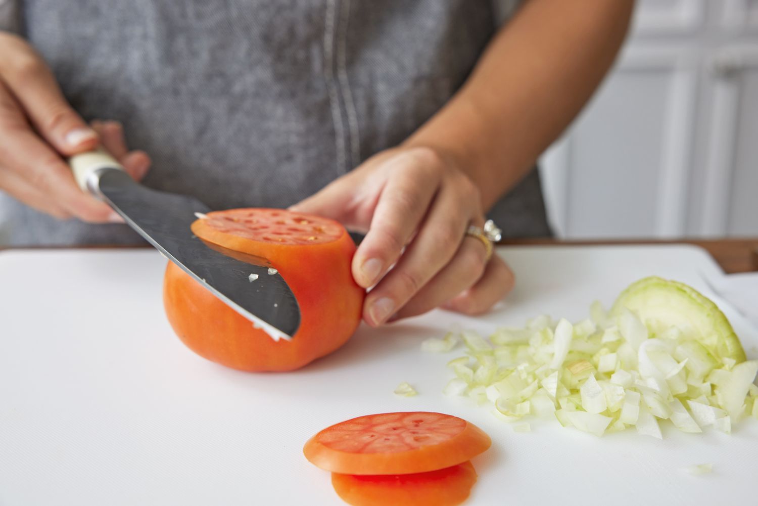 Person slicing a tomato with Material The 8-Inch Knife