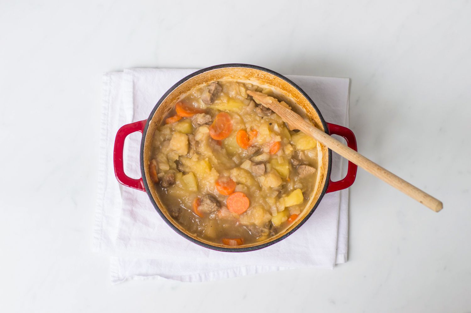 Finished Scottish stovies recipe in a Dutch oven with a wooden spoon