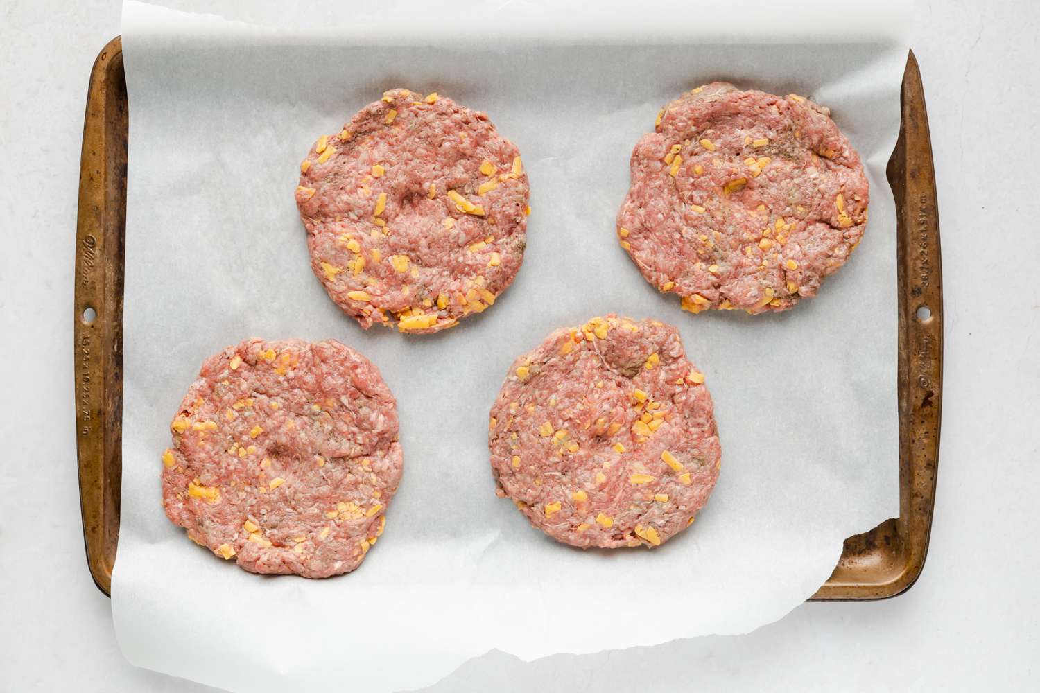 shaped burger patties on a baking sheet 