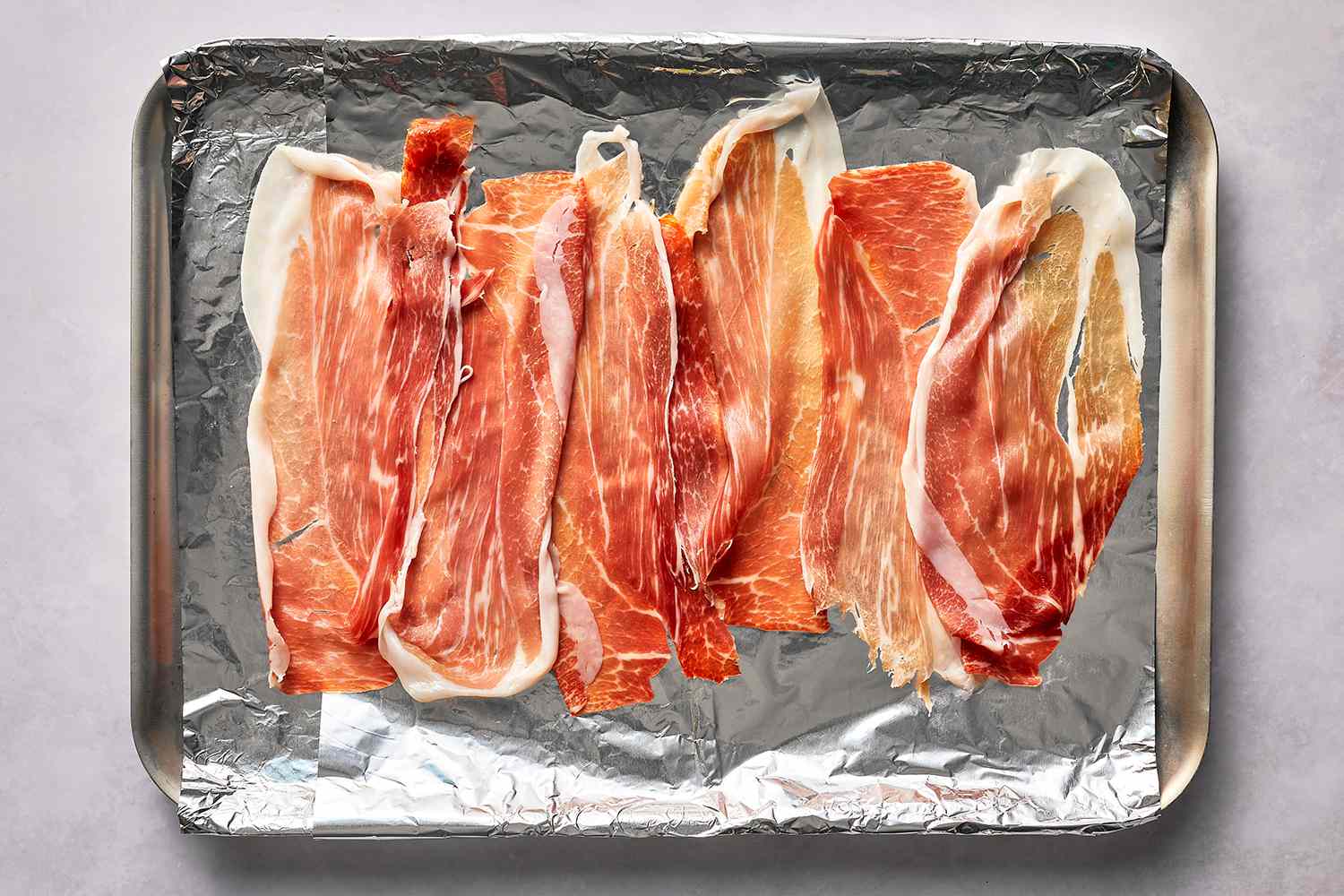 Prosciutto slices on an aluminum foil lined baking sheet 