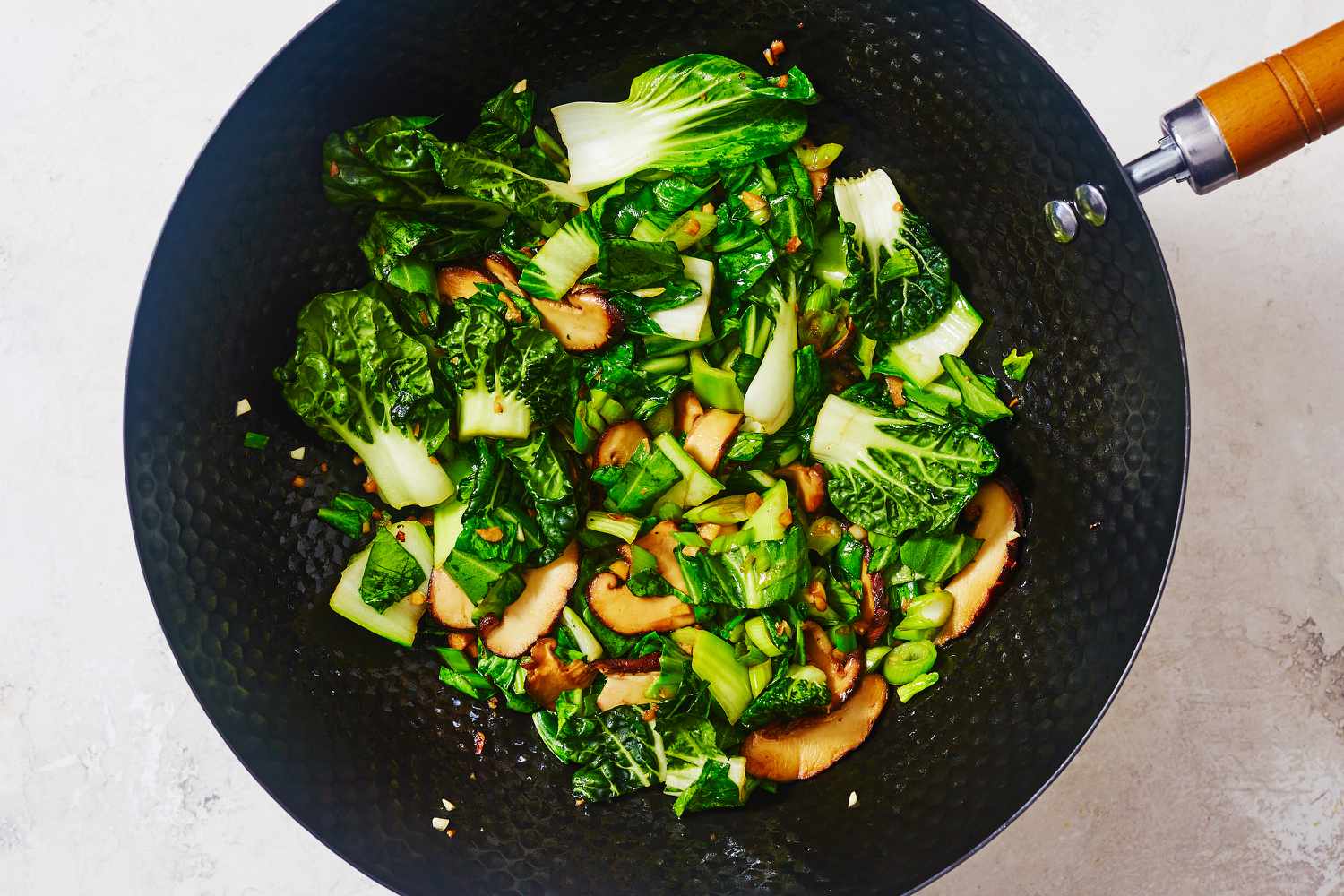 Bok choy, mushrooms, and scallions in a wok