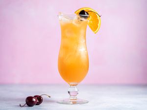 Classic hurricane cocktail with a cherry and orange slice garnish