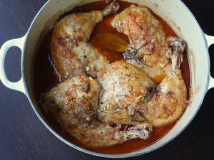 Four whole chicken legs in a dutch oven with chicken broth after braising