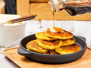 Cornmeal johnnycakes in a skillet with maple syrup