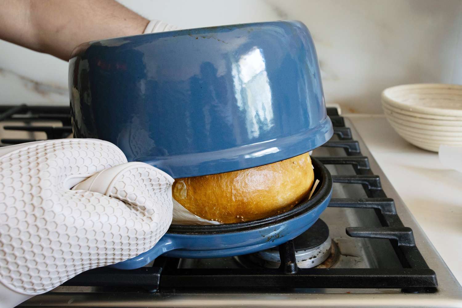 Lid being lifted from a blue Our Place Cast Iron Hot Grill that is sitting on the stovetop