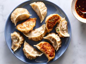 Korean Dumpling (Mandu) on a blue plate with a side of sauce 