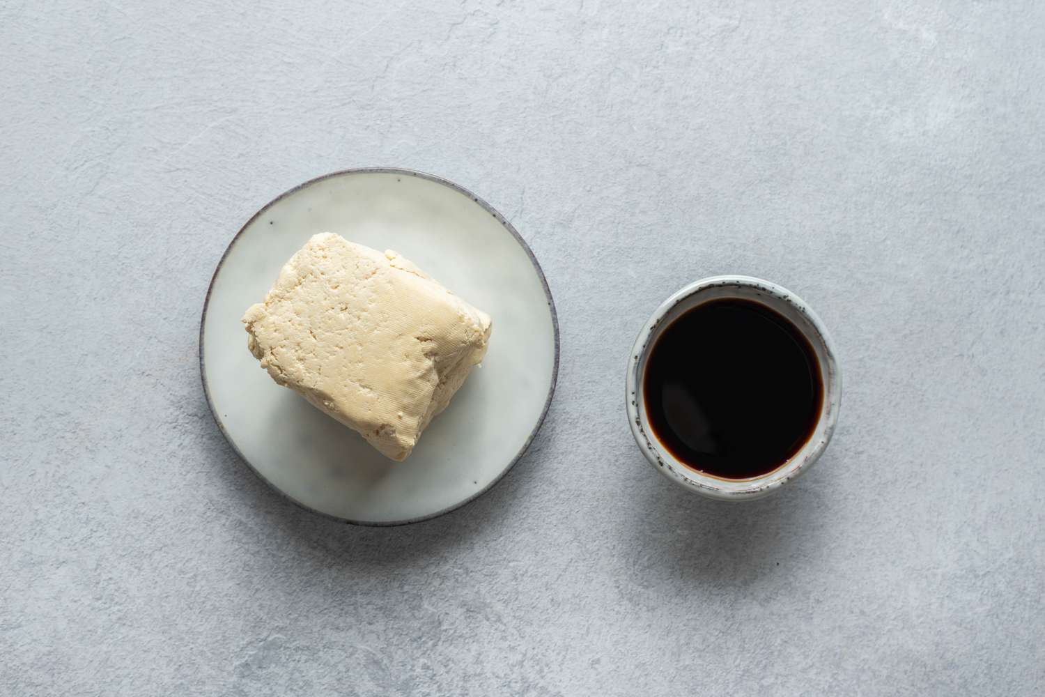 Tofu on a plate and sauce in a bowl 