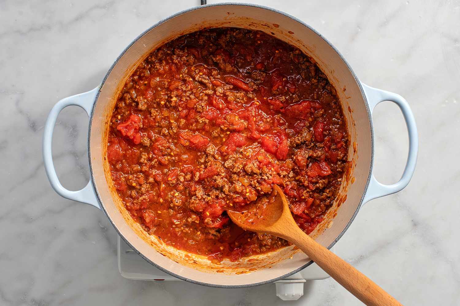 Hand-crushed tomatoes added to the dutch oven