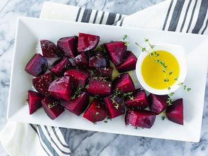 Roasted beets with olive oil and thyme on a rectangular white plate