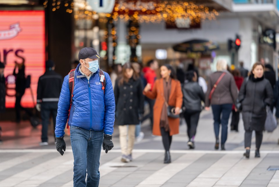 Sweden's daily case rate has spiked to a record 5,990, Pictured: A man wearing a face mask walks in the street in Stockholm