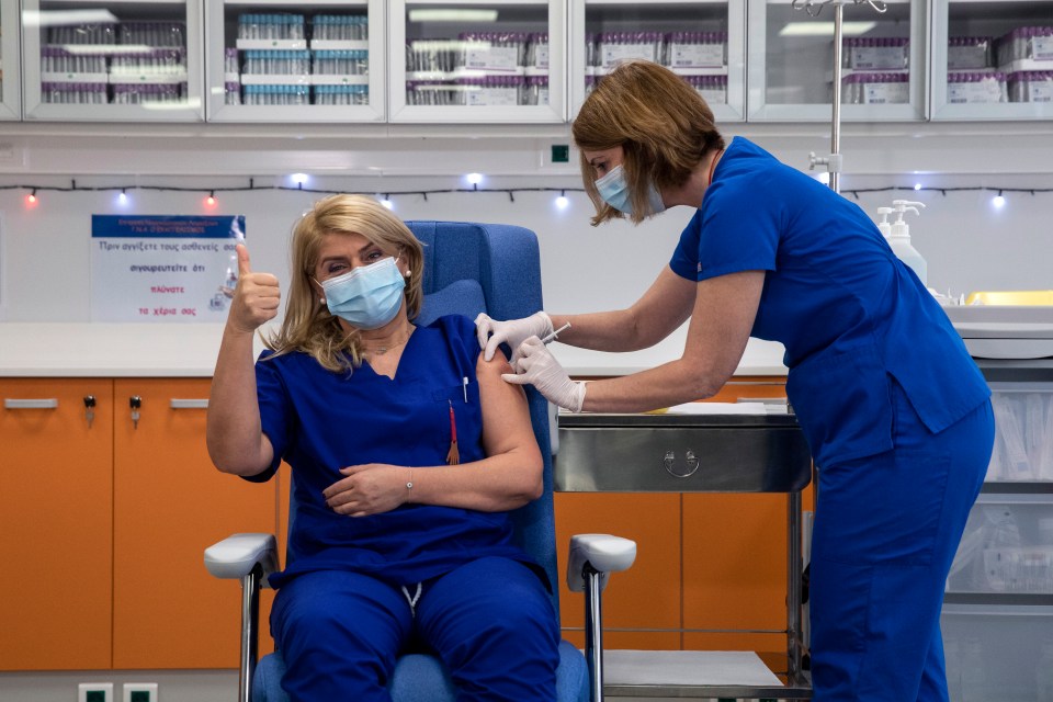 A Greek nurse gives the thumbs up as she is injected in Athens