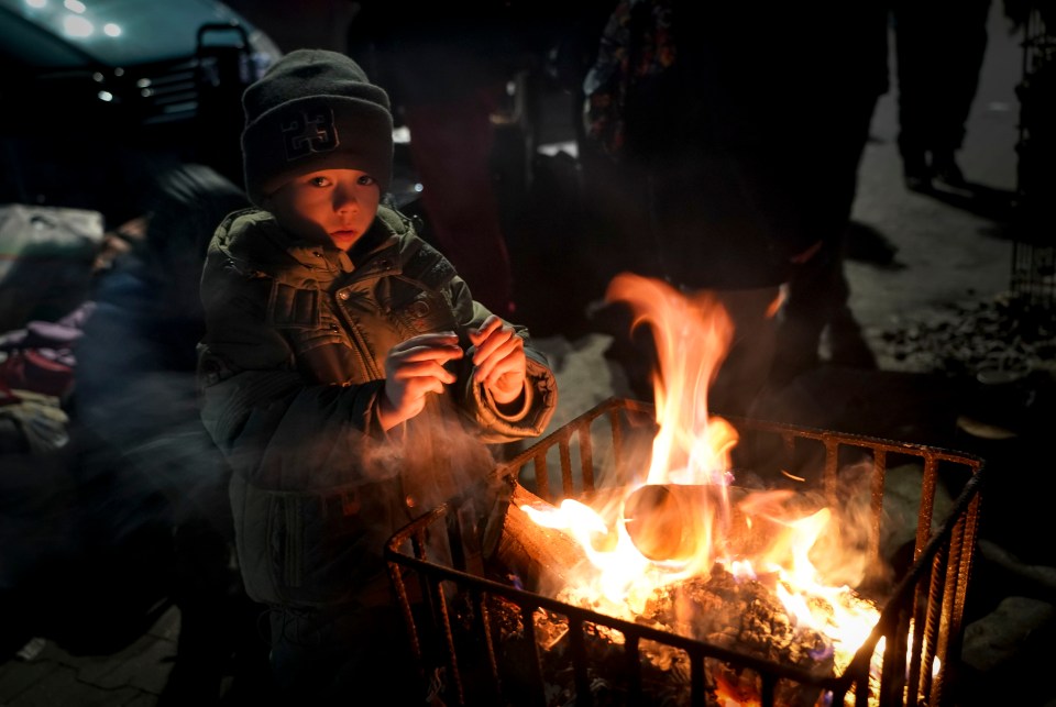 In Pzermysl, three-year-old Danylo Mikrukov warmed his tiny hands over a fire at a makeshift refugee camp after a gruelling three-day trek from Ukraine