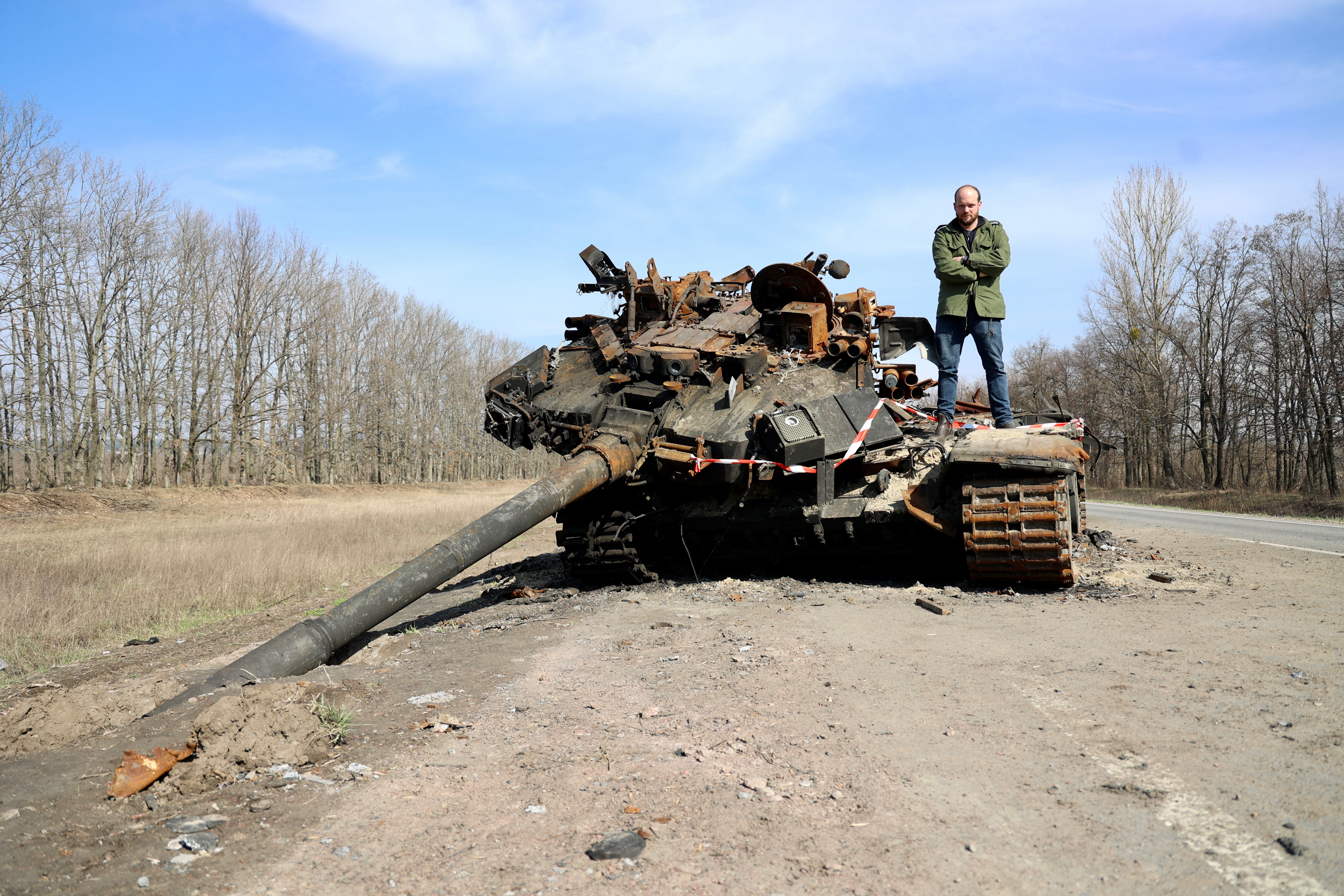 The Sunâs Jerome Starkey stands on a destroyed Russian battle tankCredit: Peter Jordan