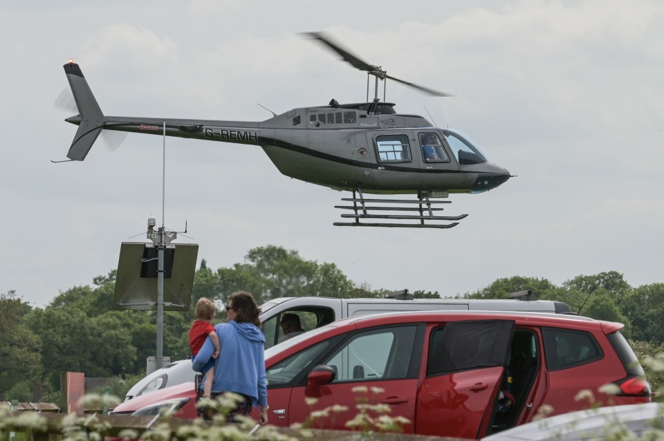 A helicopter flies low over parked cars