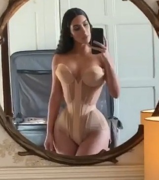 Kim Kardashian shows off her tiny waist as she squeezes into a skintight corset