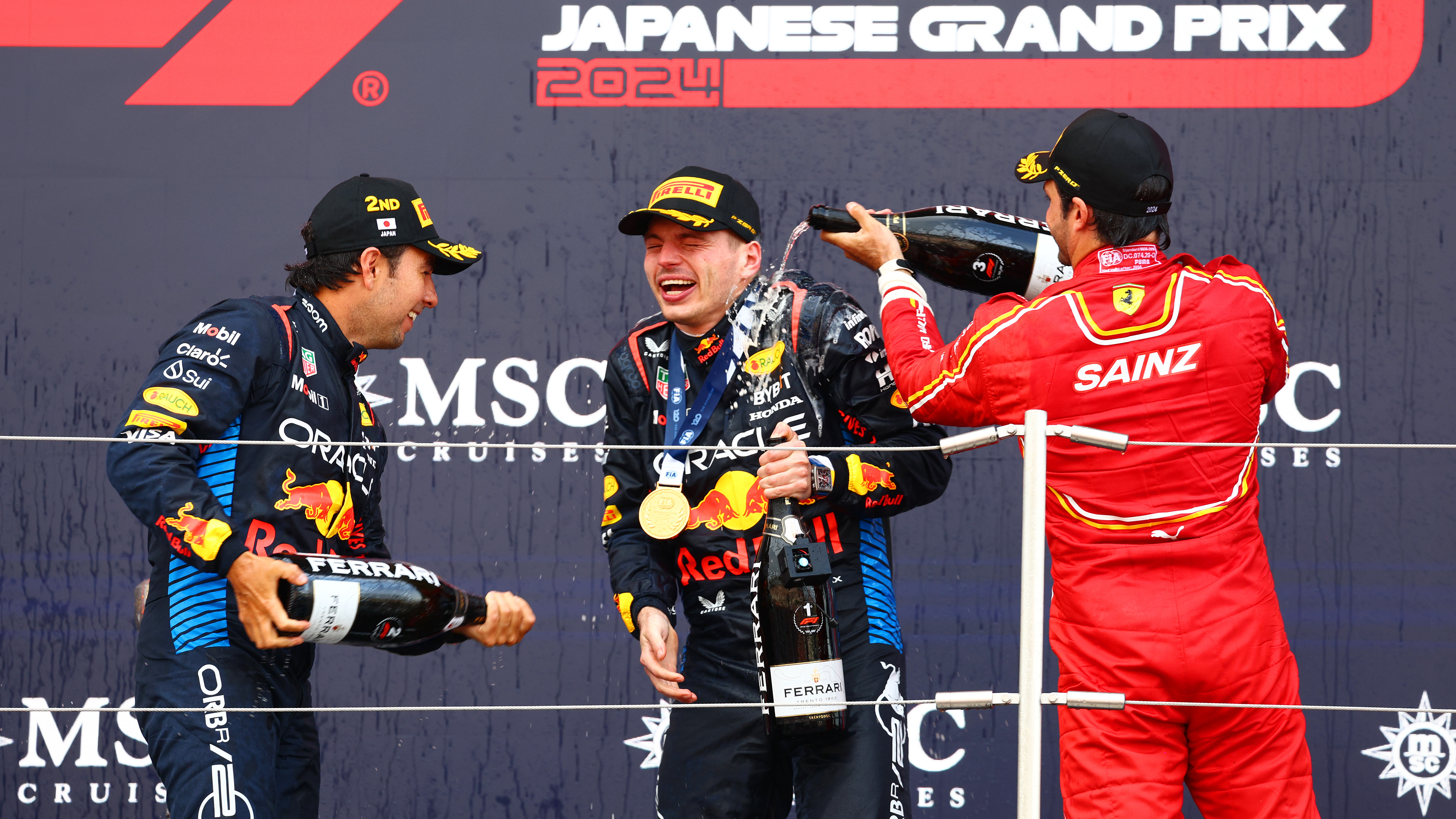 Verstappen celebrates on the podium with Sergio Perez and Carlos Sainz