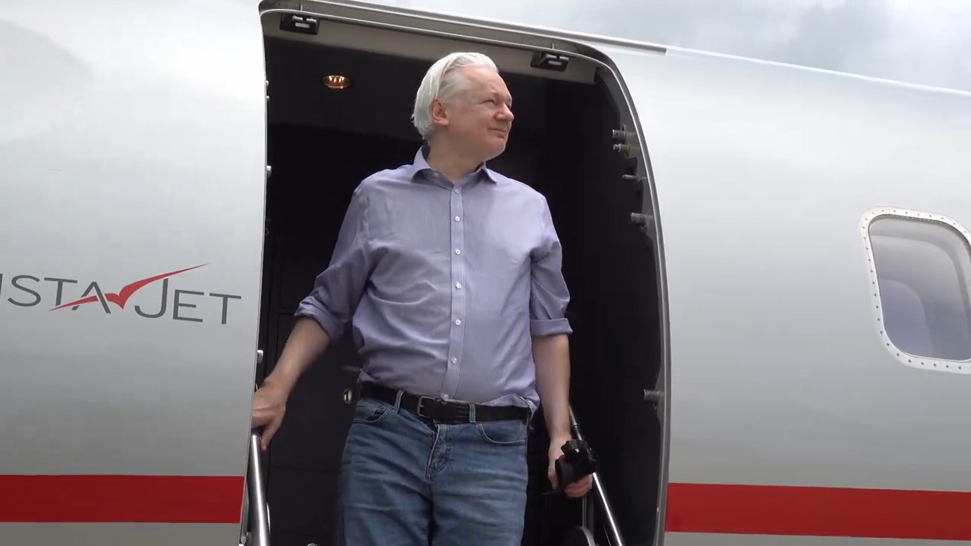 Julian Assange on the steps of his plane in Bangkok