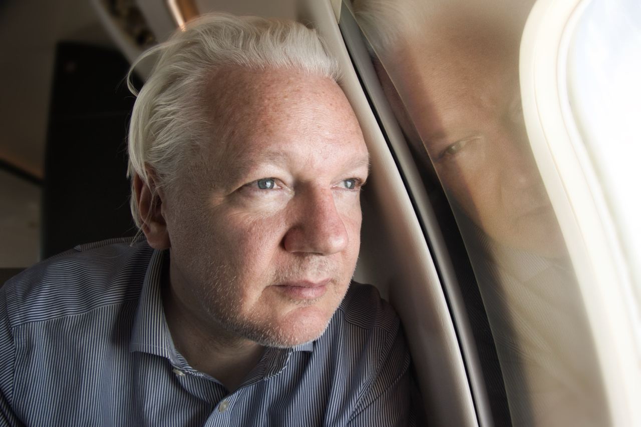 Assange snapped looking out the plane window on his way to Thailand