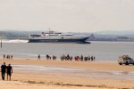 a group of people walking on the beach near a steam-packet.com ship