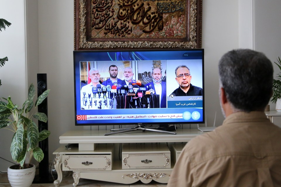 A man watches Iranian TV news covering the death of Haniyeh