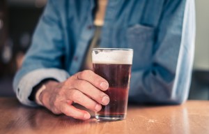 a man sitting at a table holding a glass of beer