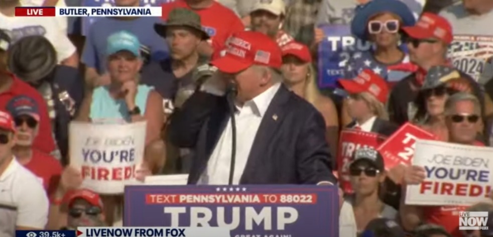 Footage shows Trump just before he dived for cover at the rally - with a hand pressed to his ear