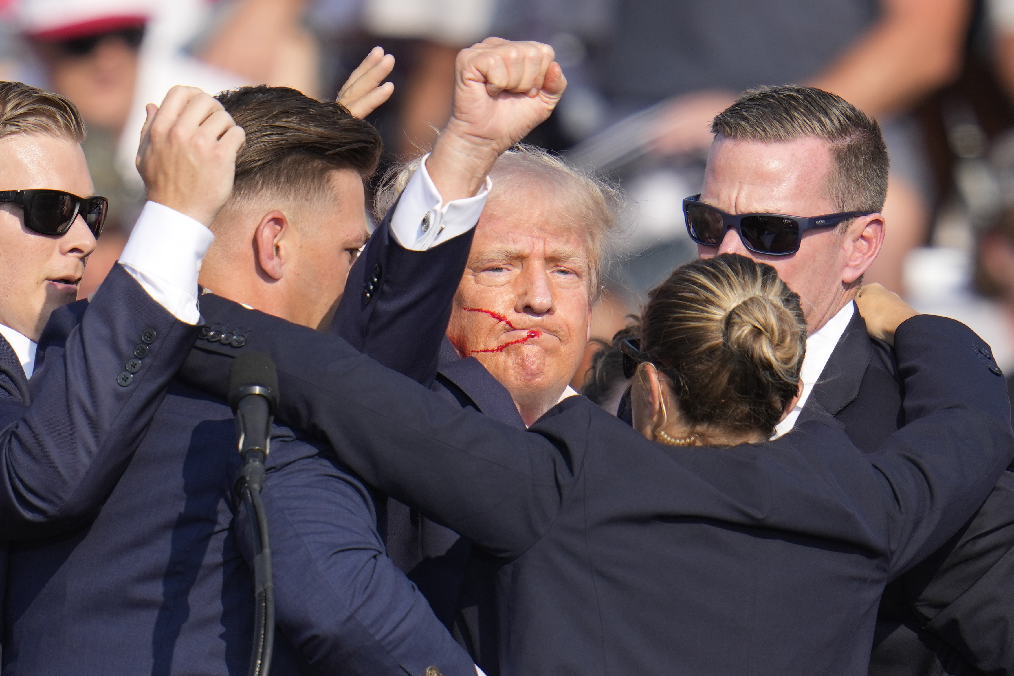 Defiant Trump raised a fist to the shocked crowd as he was bundled away