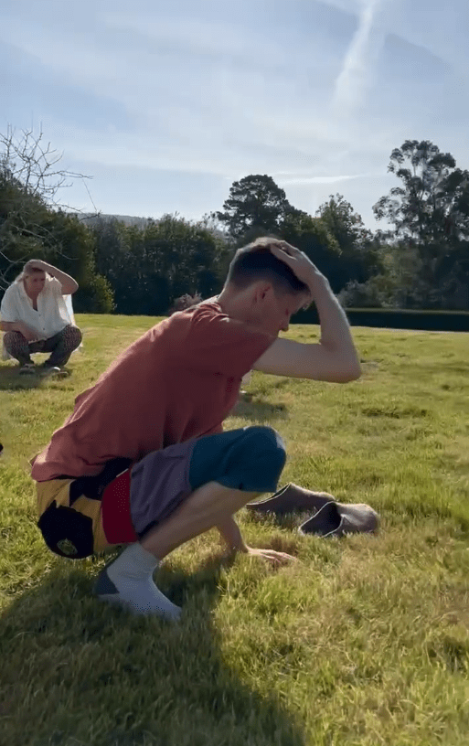 The retreat guests sit outside hitting themselves on the head