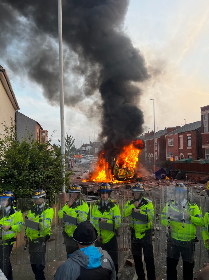 Lies spread on social media have triggered violence after the Southport stabbings, above Southport police stand as a van burns