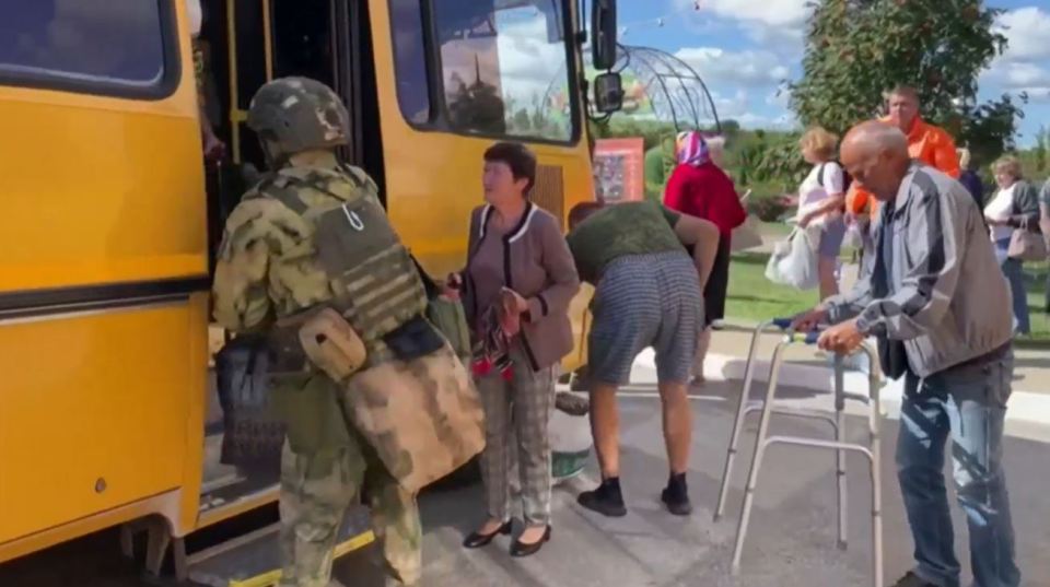 A Russian soldier ushers people into buses to be evacuated from Belgorod