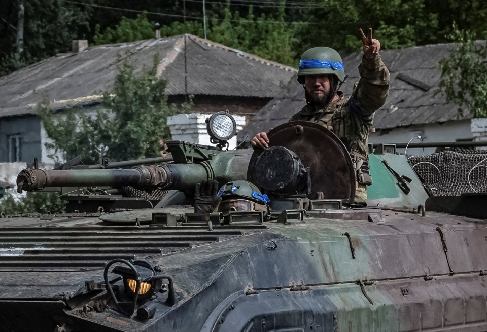 Ukrainian servicemen ride a BMP-1 infantry fighting vehicle and give a 'V' for victory sign