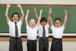 a group of children in school uniforms are raising their arms in the air