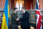 two men are shaking hands in front of a british flag