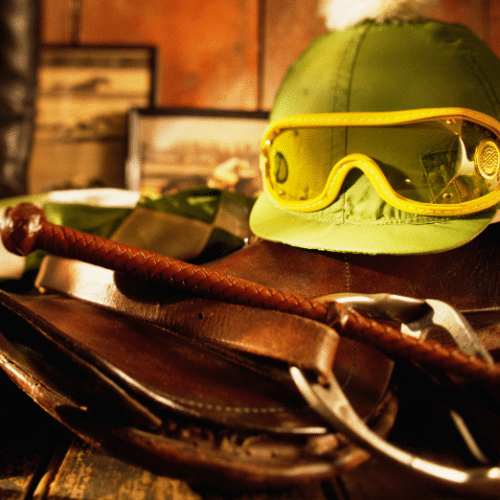 Photo with a helmet, riding crop and binoculars sitting on a desk.