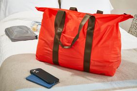 Away The Packable Carryall on a bed near an iPhone