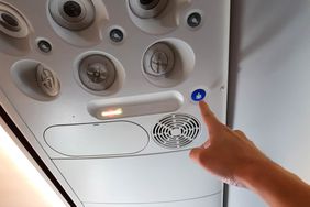 A hand pressing the button in the passenger air plane to call flight attendant