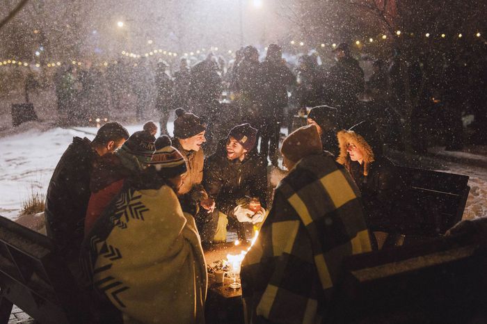 A group of people under blankets around a fire at The Great Northern Festival in Minnesota