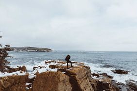 Person taking photos of the cliffs in Acadia during winter